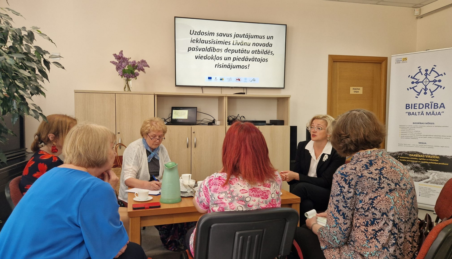 daudz cilvēku sēž ap galdu