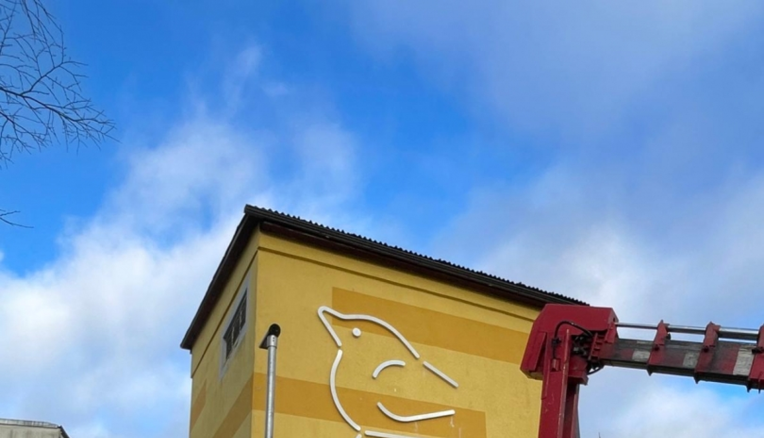 ar celtni uzstāda metāla skulptūru putniņu