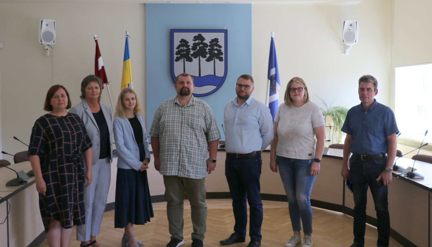 vairāki cilvēki stāv pie karoga