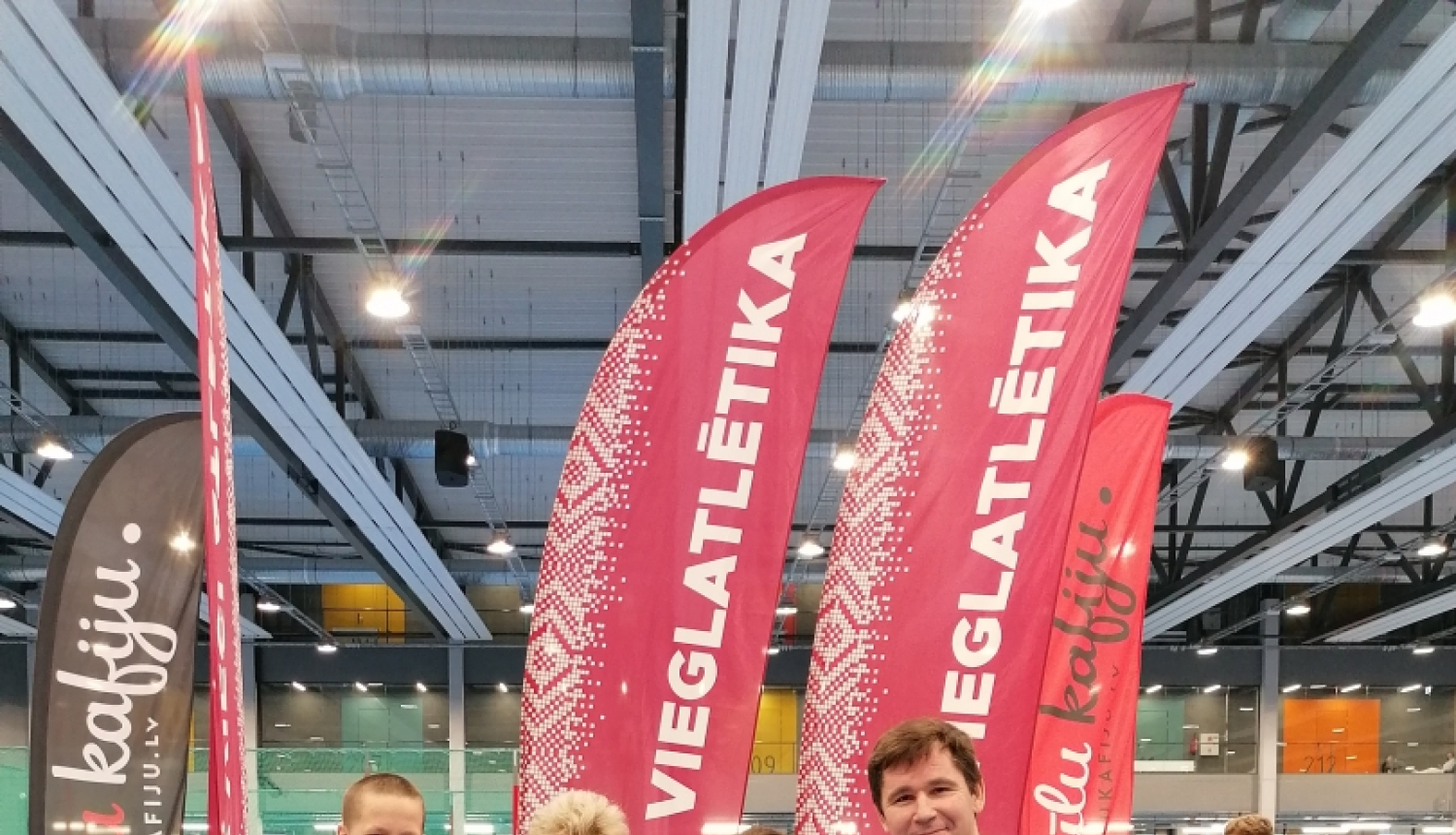 četri cilvēki pie pjedestāla ar medaļām