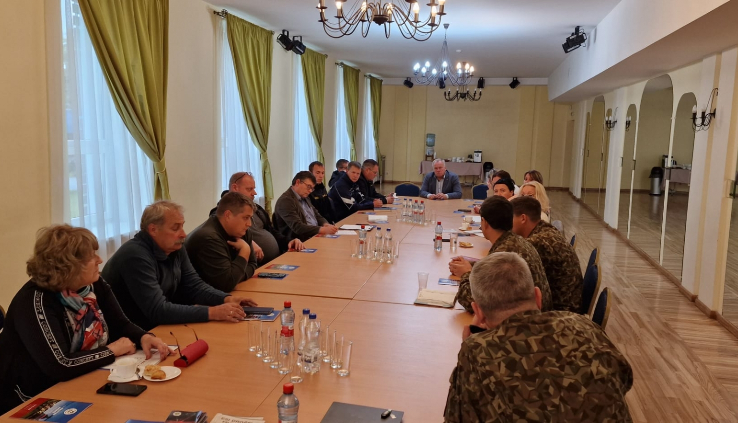 Daudz cilvēku ap galdu, sapulce