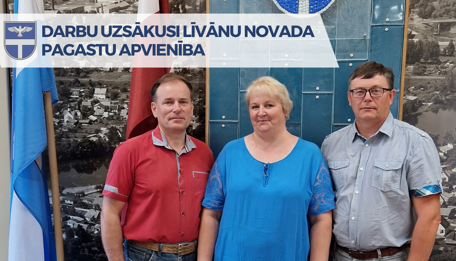 divi vīrieši un sieviete stāv pie karoga