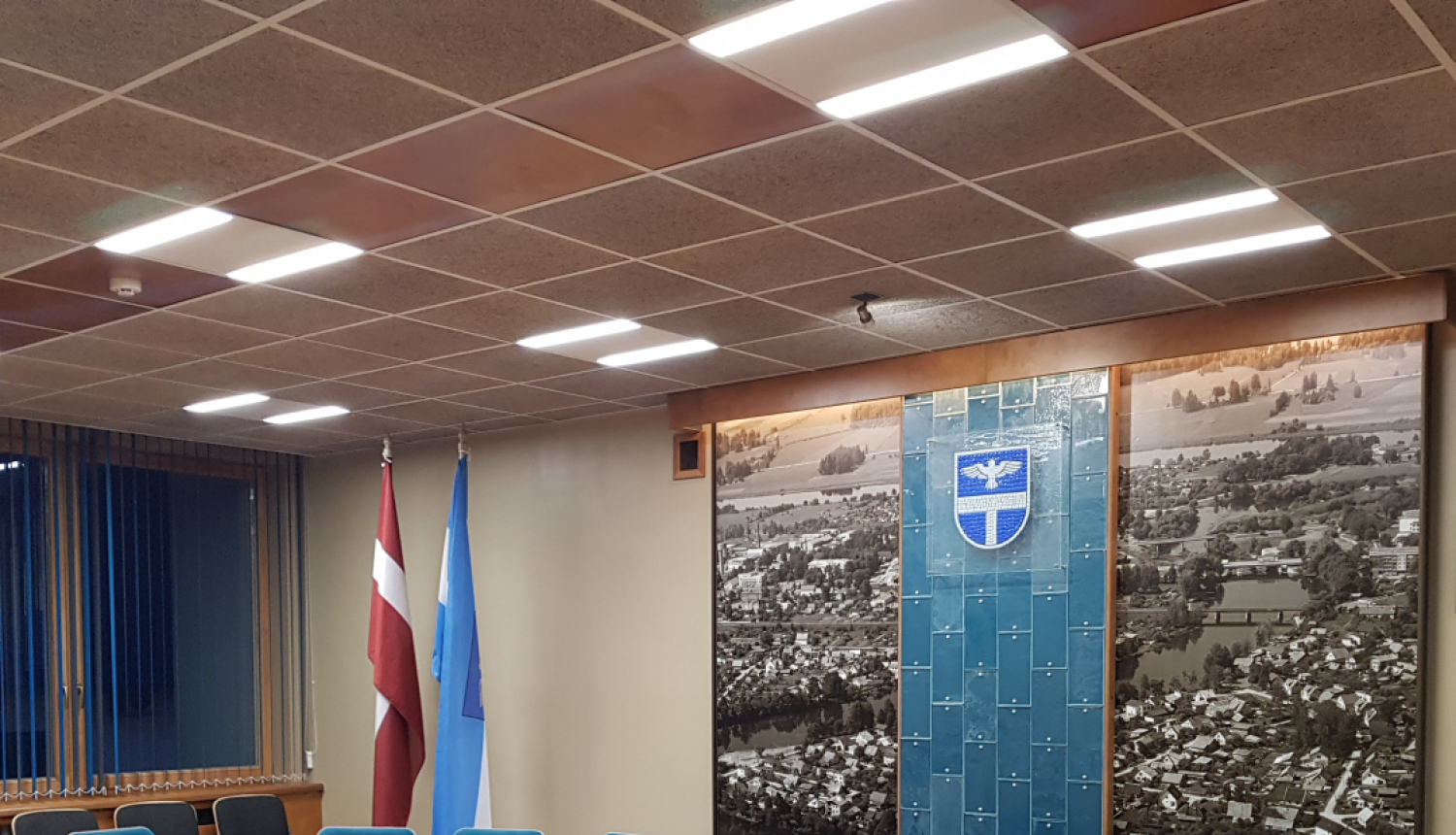 Sēžu zāle ar galdu, krēsliem un karogiem