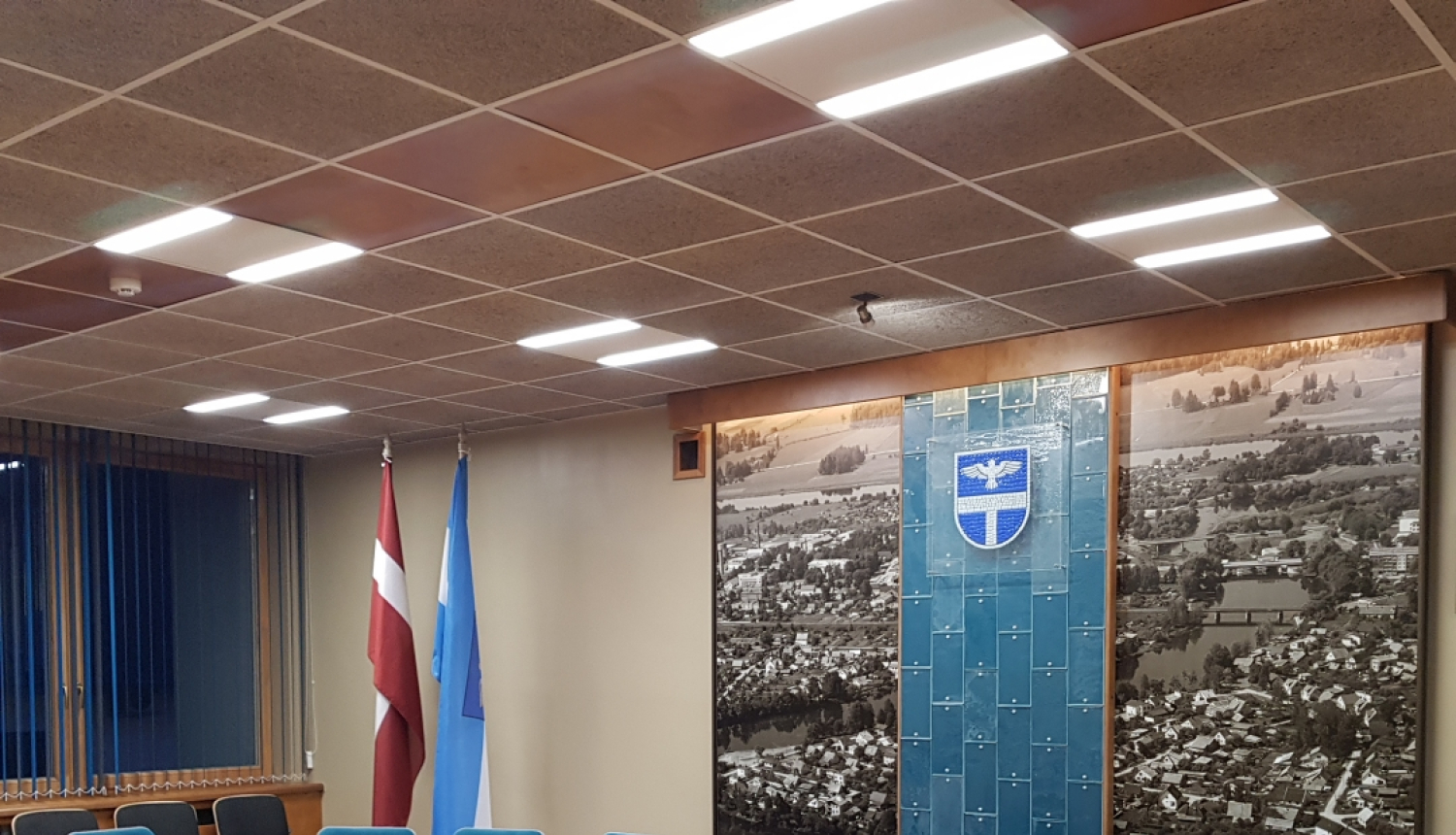 Sēžu zāle ar galdu, krēsliem un karogiem