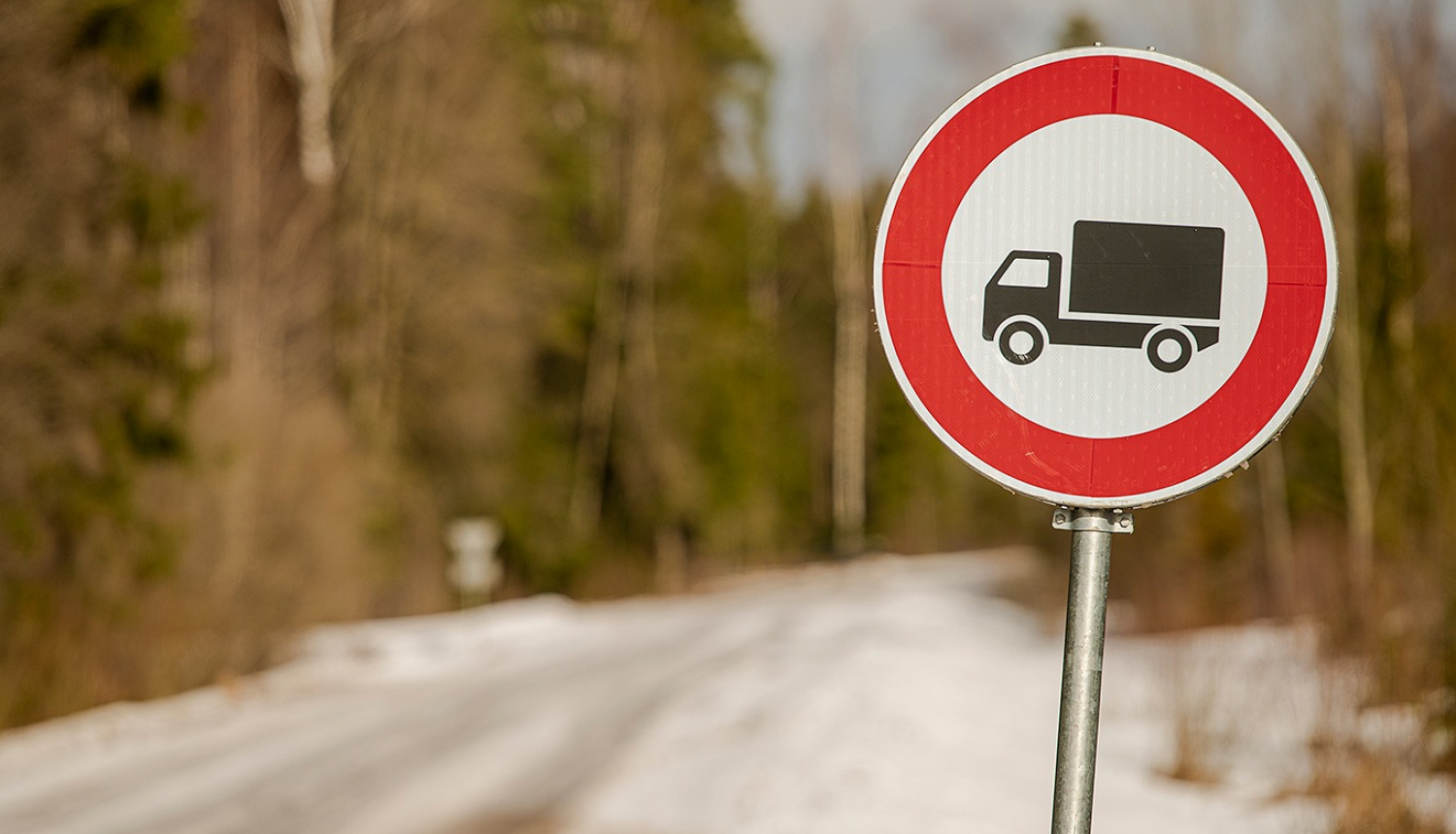 ceļa zīme ar smago auto unslikts ceļš fonā