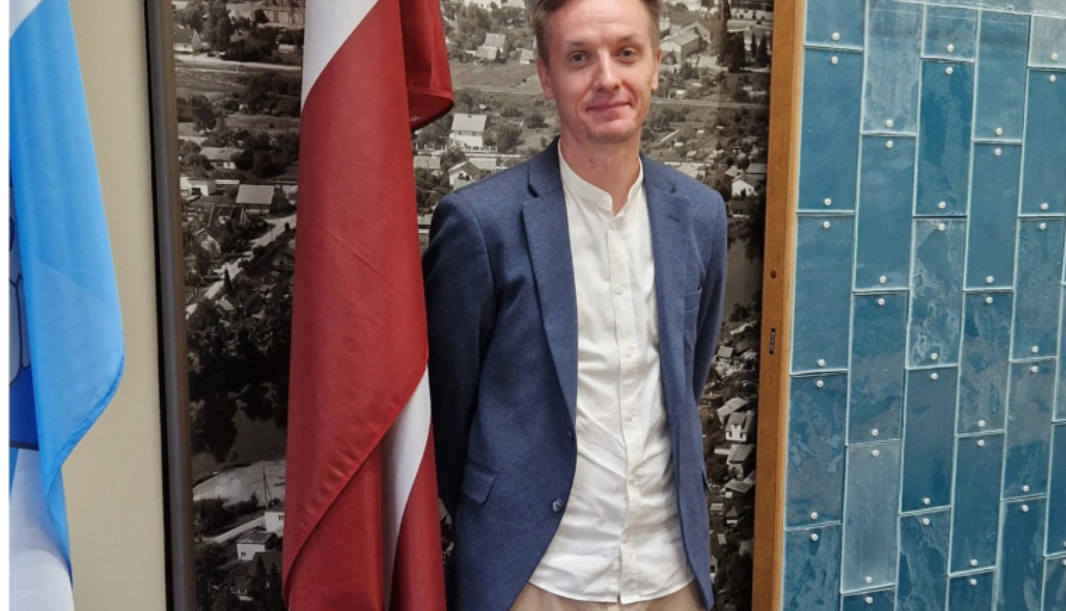 vīrietis stāv pie sienas ar karogiem