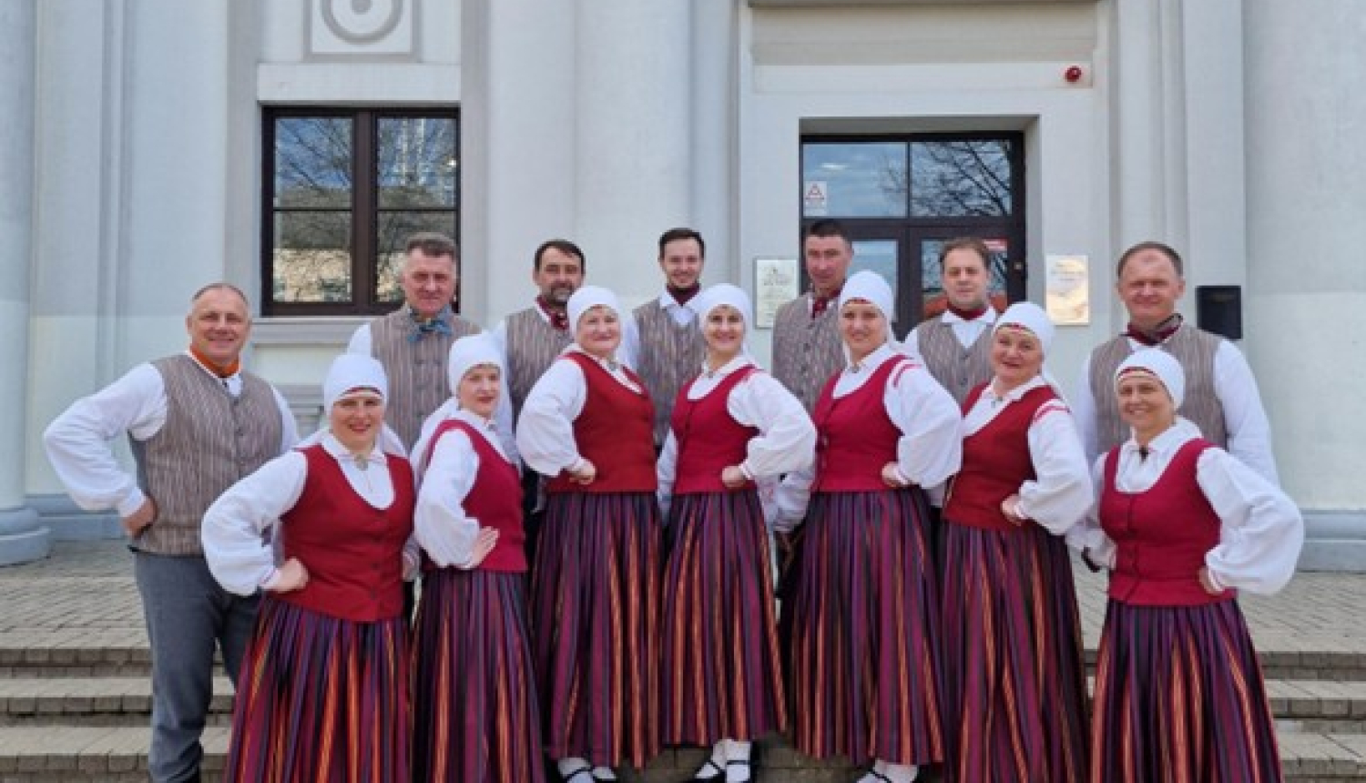 cilvēki tautastērpos stāv 